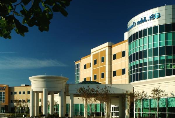 Exterior photo of Owasso Hospital and Medical Office Building. Four-story hospital entrance against bright blue skies.